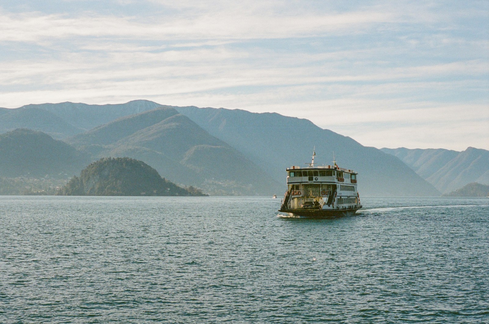 A ferry crossing Lake Como beneath layered mountain ridges
