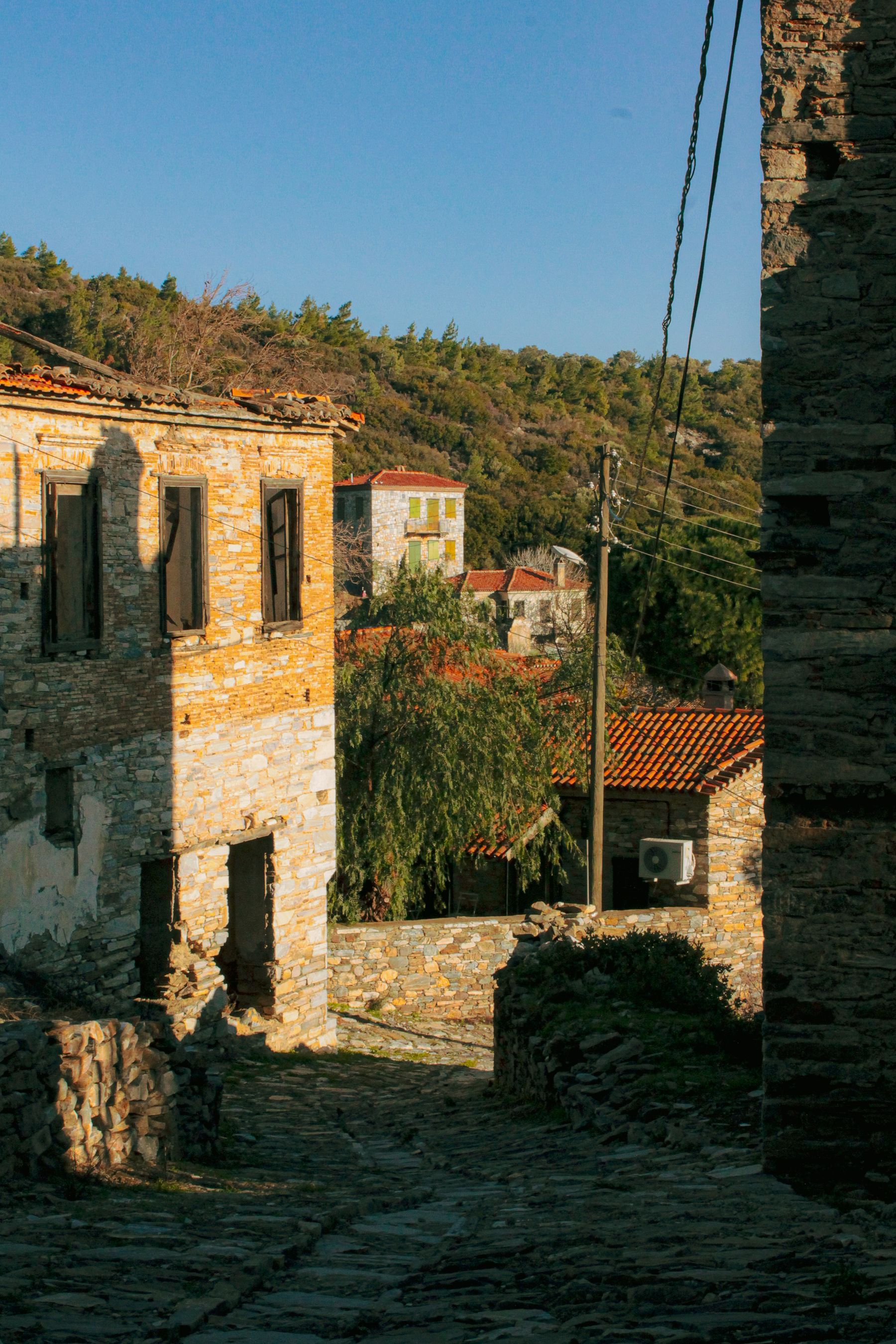 Sunlit stone buildings above a quiet cobbled lane in an Italian village